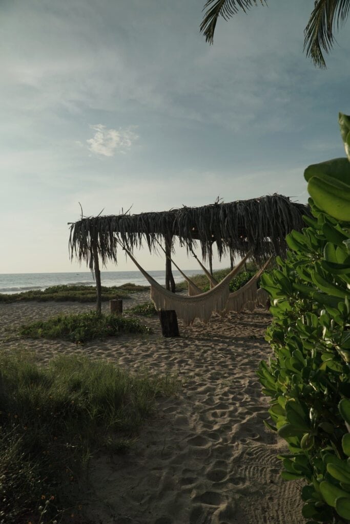 Hammocks under a palm-leaf palapa on the beach at Casona Sforza