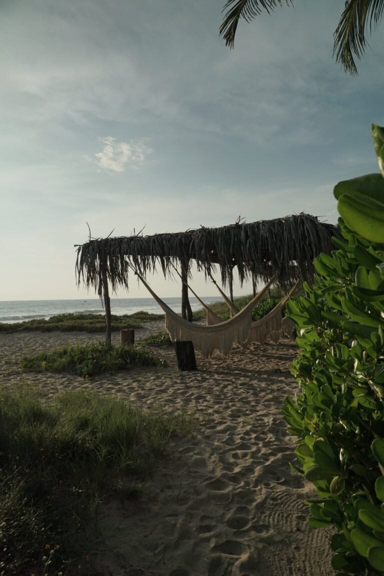Hammocks under a palm-leaf palapa on the beach at Casona Sforza