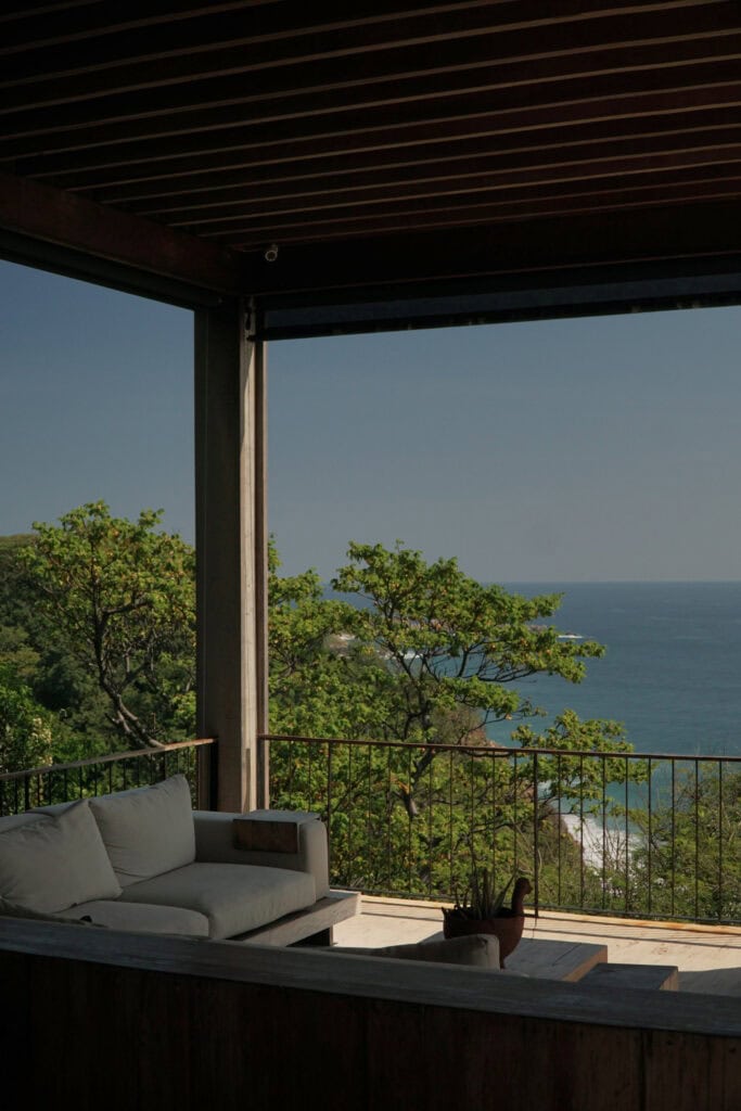 Shaded terrace sofa with ocean and jungle views at La Valise Mazunte